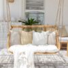 outdoor hanging chair with white pillows and throw