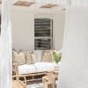 teak lounge with white seat cushions with white curtains