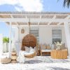 Dark wicker hanging chair with white pillows and throw