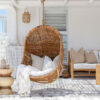 Dark wicker hanging chair with white pillows and throw