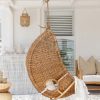 Dark wicker hanging chair side view with white pillows and throw