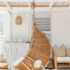Dark wicker hanging chair side view with white pillows and throw