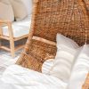 Dark wicker hanging chair close up view of rattan and has white pillow sitting inside